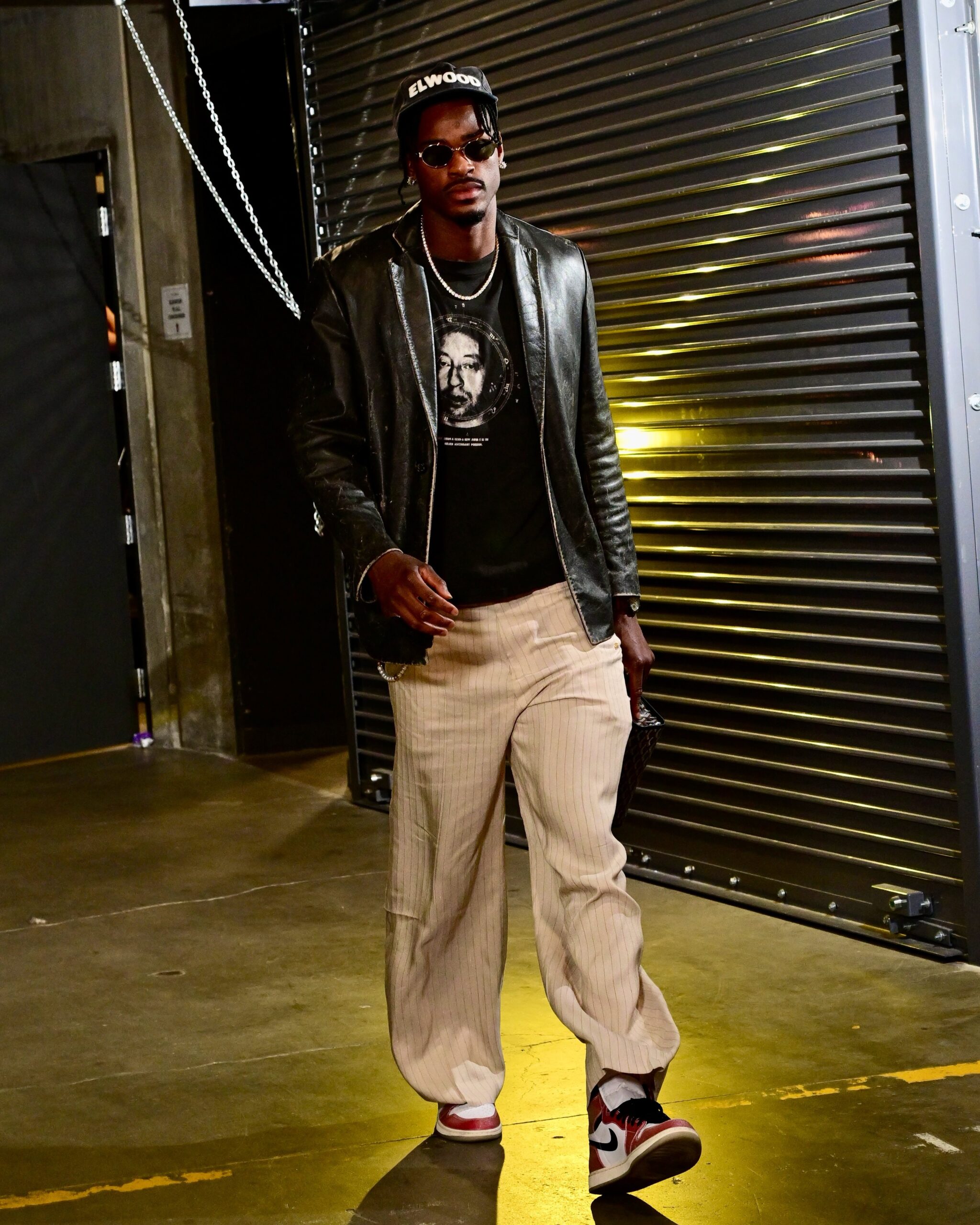 Jarred Vanderbilt wearing The Row Black Genki Leather Jacket, Golden Goose Unisex sweatpants in ecru and sand striped cotton and linen and Nike Trophy Room x.