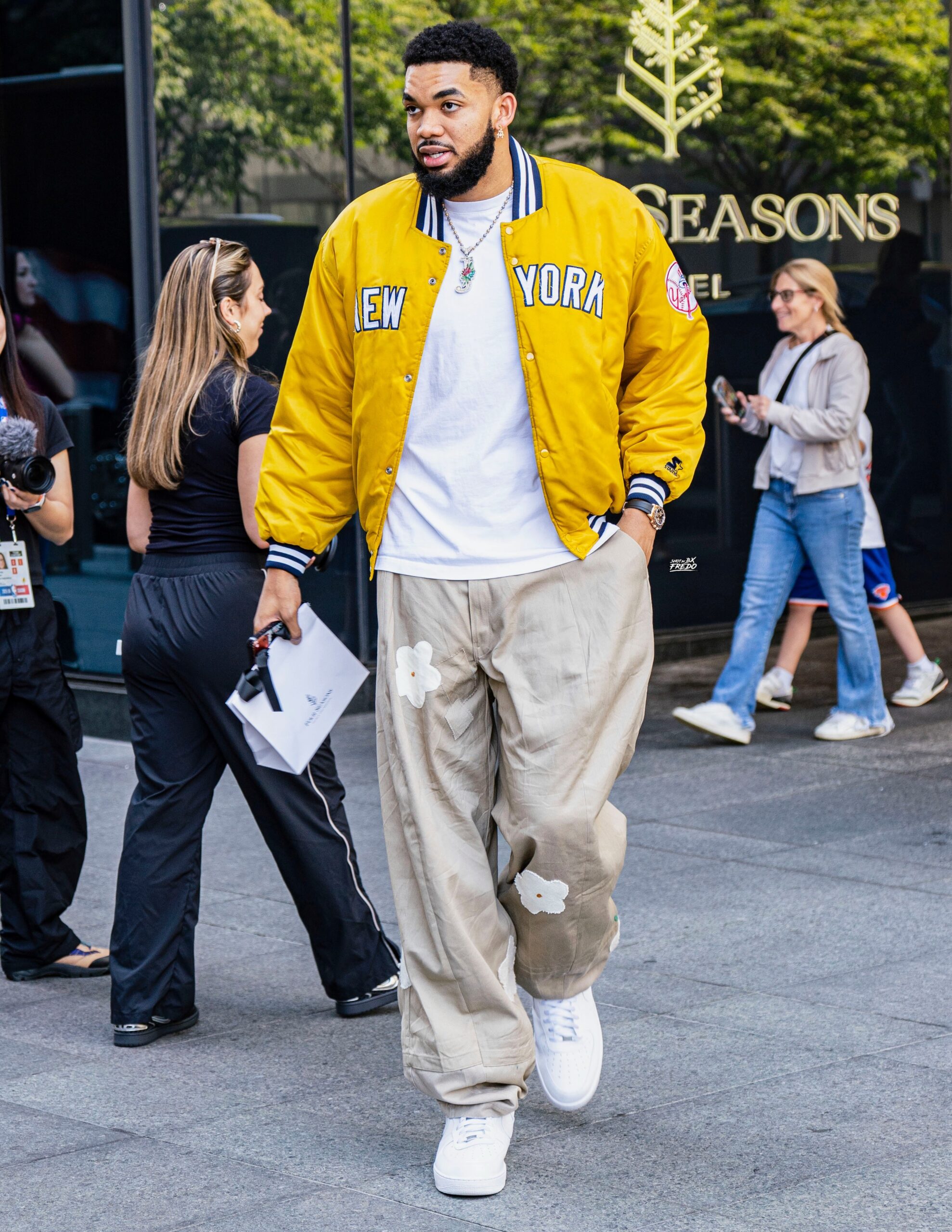 Karl Anthony Towns wearing William Jacket NY Yankees Dugout Satin Jacket, Joshua Samuels FO Baggy Trou – Beige – Flower Edition and Nike Nike Air.