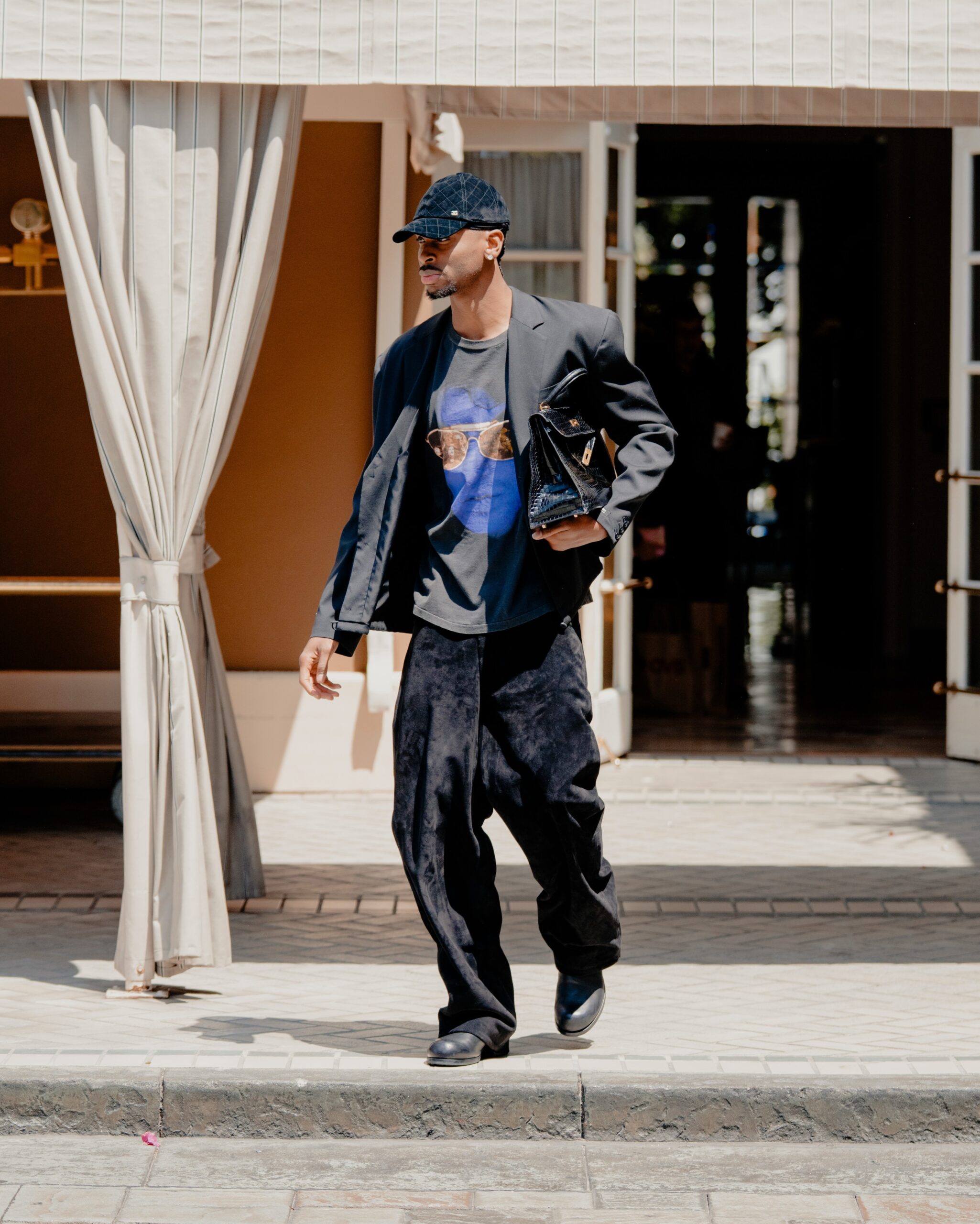 Shai Gilgeous Alexander wearing CHANEL Suede Calfskin cap, Hermes 1981 Kelly 32 crocodile-embossed two-way handbag and Saint Laurent black Velvet trousers.