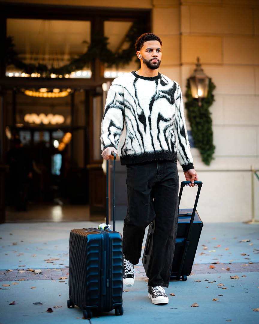 Ajay Mitchell wearing Fashion Nova Marble Effect Crewneck Sweater – Black/combo, Carhartt Single knee black jeans and Converse Chuck taylor throwback.