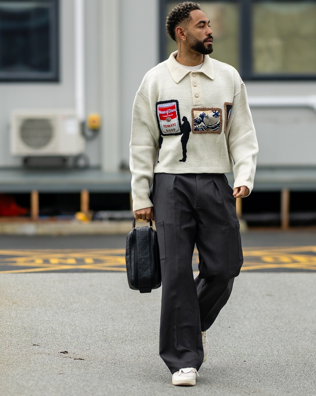 Matheus Cunha wearing House of Errors Knitted gallery sweater in black and Maniere De Voir Luca – relaxed fit pleated pocket pants – grey.
