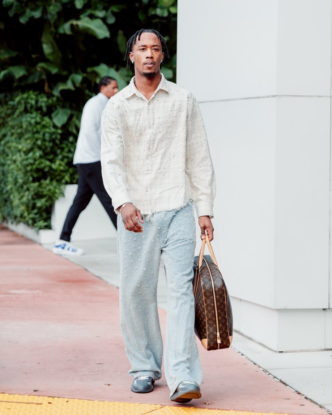 Ronald Holland II wearing Birth Of Royal Child 20K pearl diamond shirt beige, Purple Brand Jean p018 and Prada Prada america’s cup soft rubber and bike.