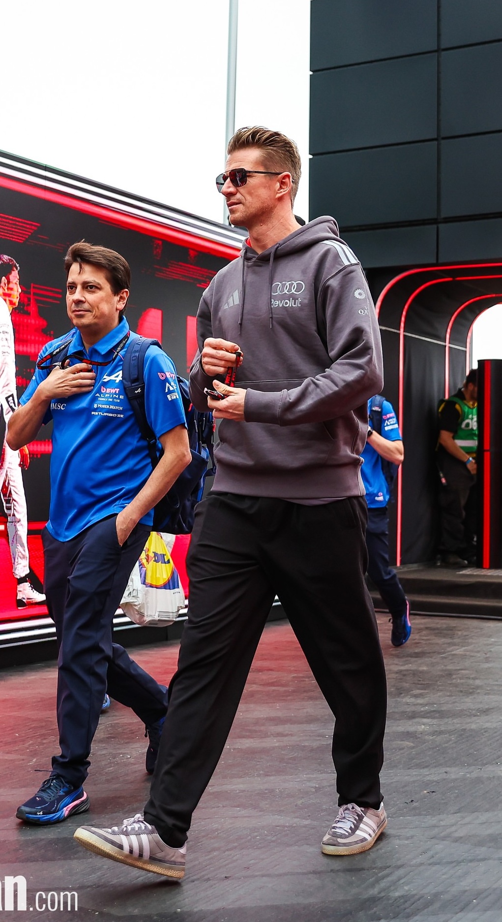 Nico Hulkenberg wearing adidas Audi revolut f1 team driver hoodie – Grey and Orange, adidas Adidas kit small logo wide pants – Black and Adidas.