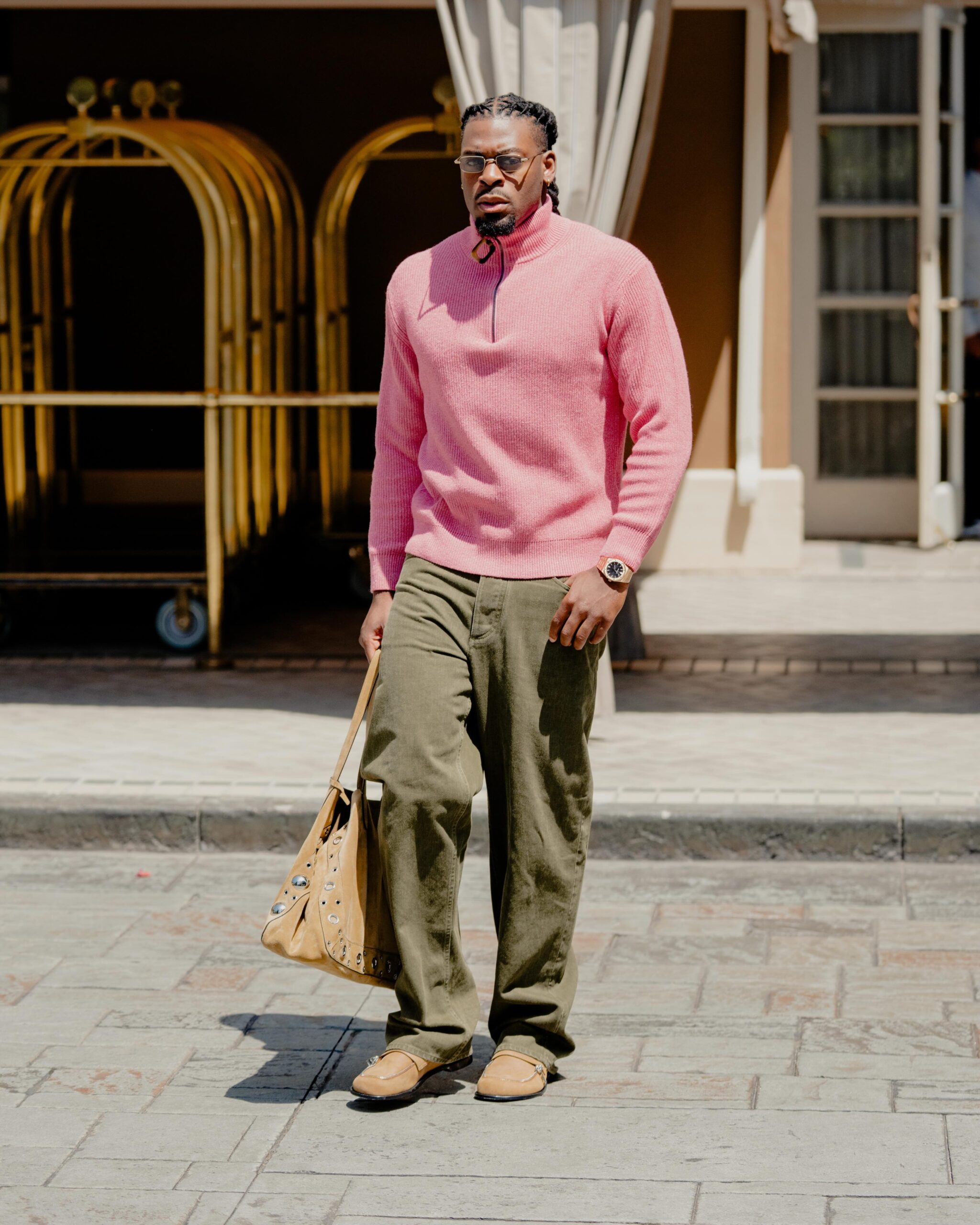 Luguentz Dort wearing JW Anderson Wool and cotton half-zip sweater pink, LEMAIRE Twisted belted pants in denim Moss Green and JW Anderson Tan Biker Loafers.