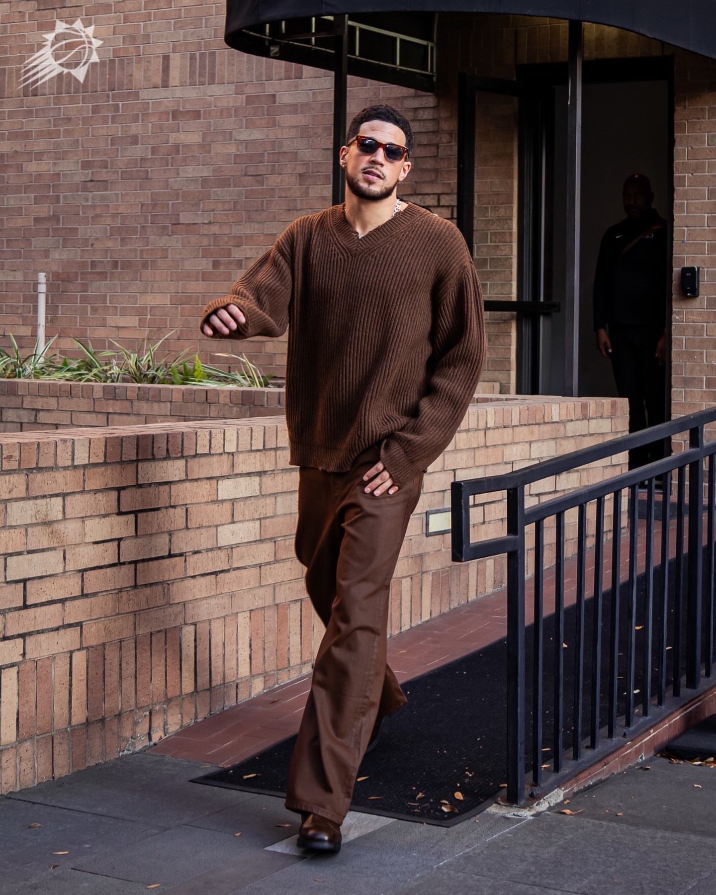 Devin Booker wearing Jacques Marie Mage Muhammad ali by jmm: Kinshasa in zoltar, Maison Margiela Ribbed v-neck brown sweater and Rick Owens Geth Brown jeans.
