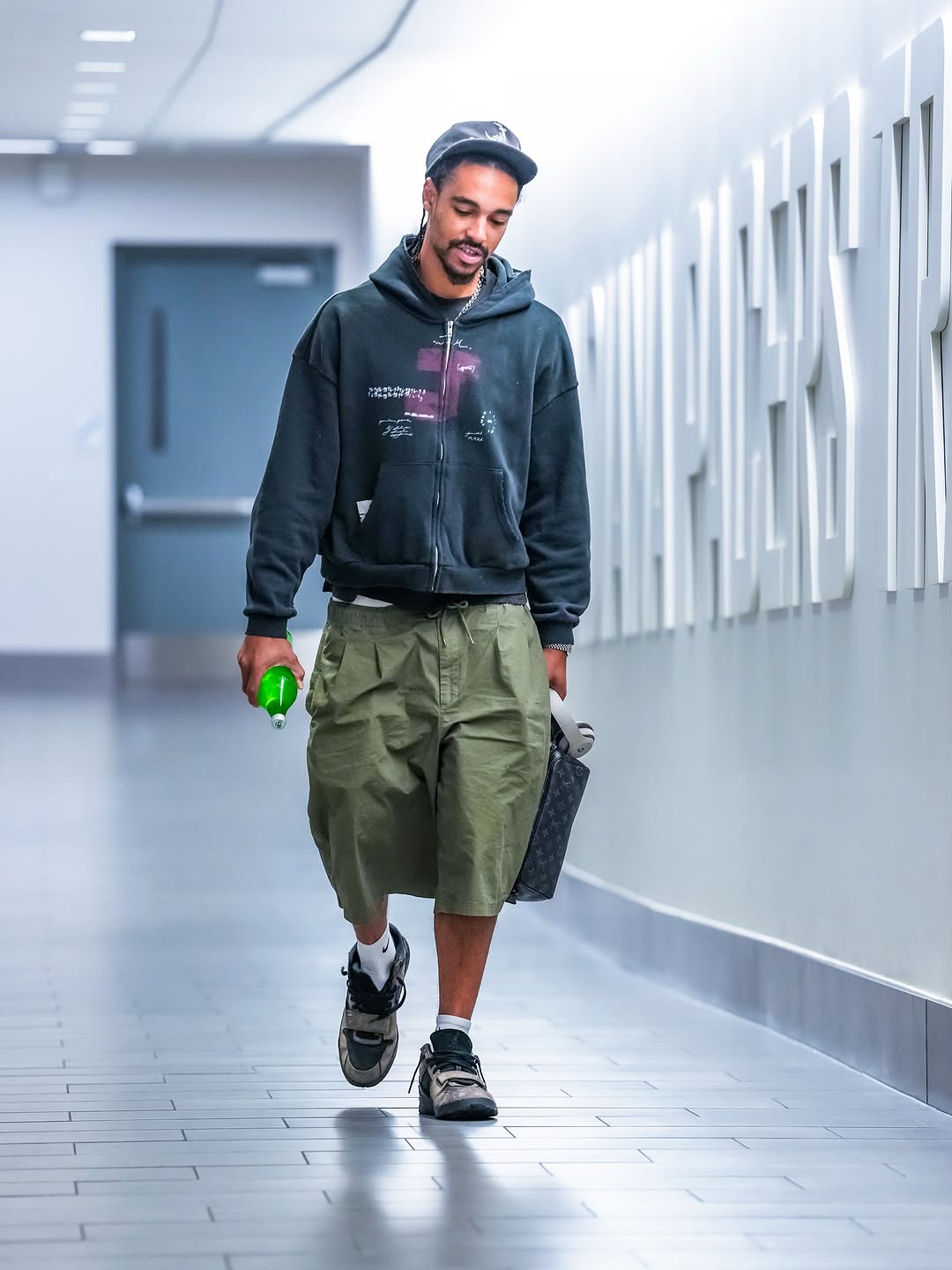 Andrew Nembhard wearing Joshua Mohamed Vintage print zip-up hoodie thick gray/black, Nike Nike club woven oversized shorts in khaki and Nike Jordan X travis.