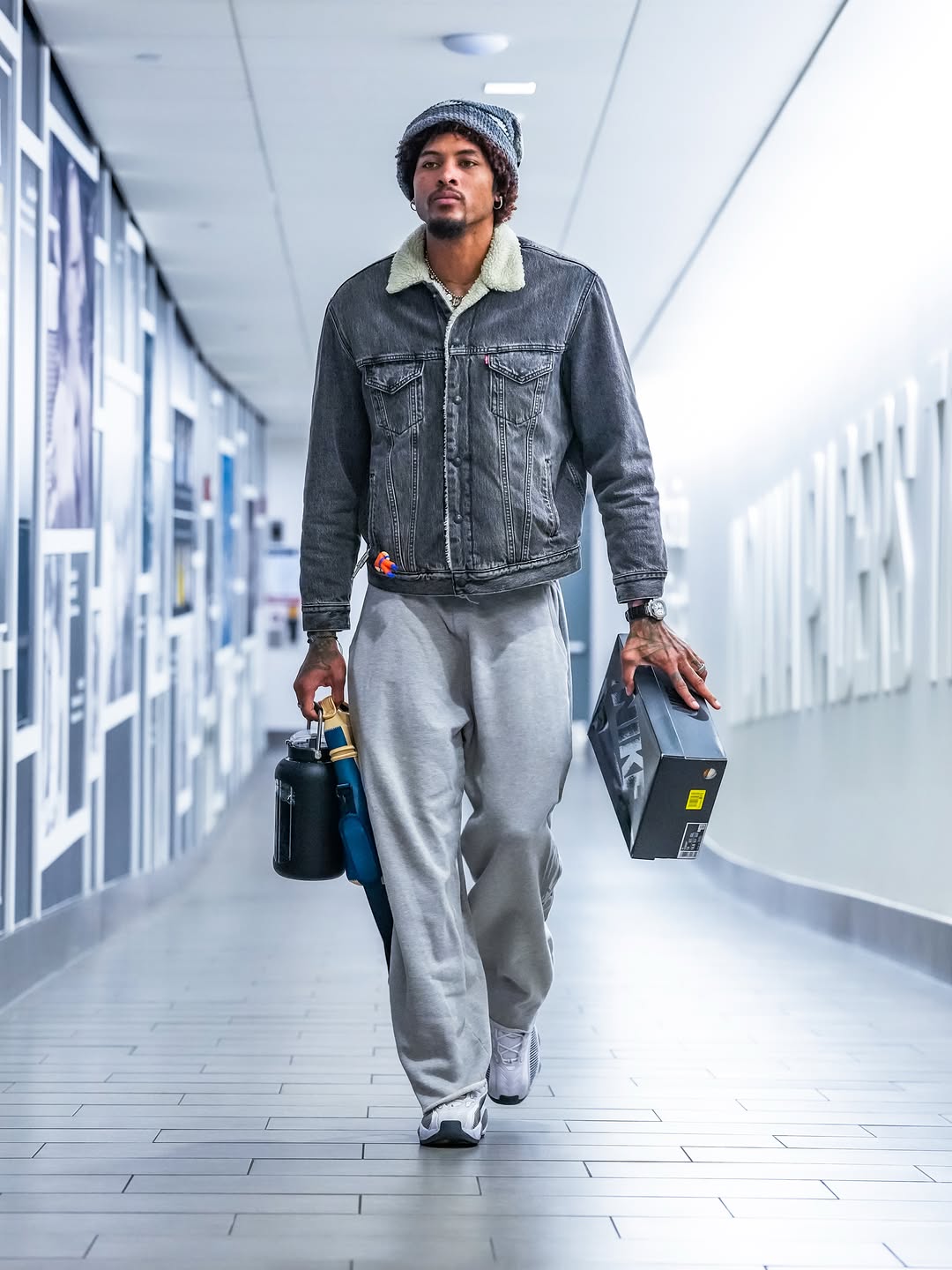 Kelly Oubre Jr wearing Levi’s Type iii sherpa corduroy trucker jacket grey, Nike Swoosh-detailed track pants grey and Nike Nocta glide sneakers black.