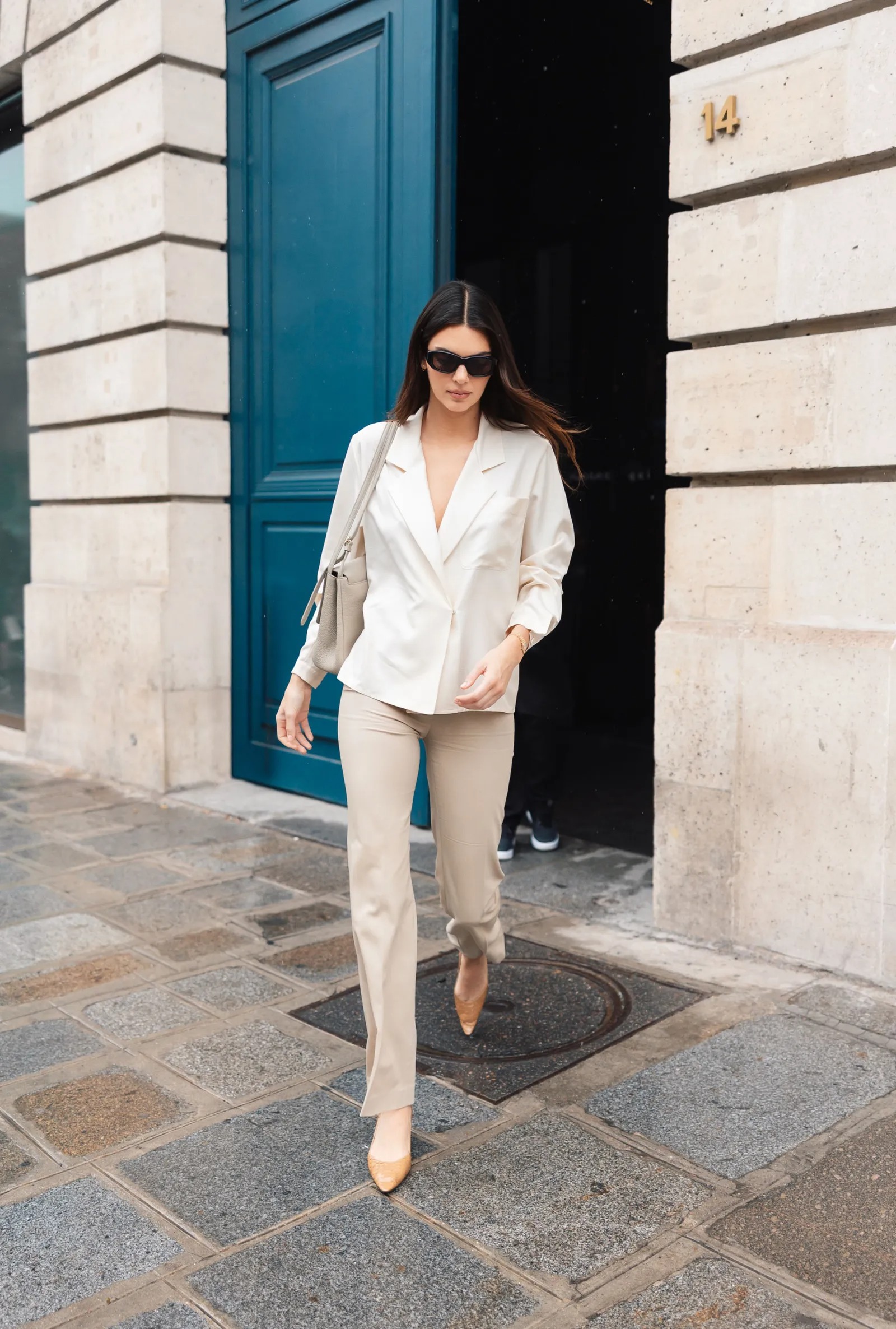 Kendall Jenner wearing Aritzia Baker Classic satin button-up shirt cream, The Fold Clever crepe doppio alzira beige trousers and The Row Liisa kitten three.