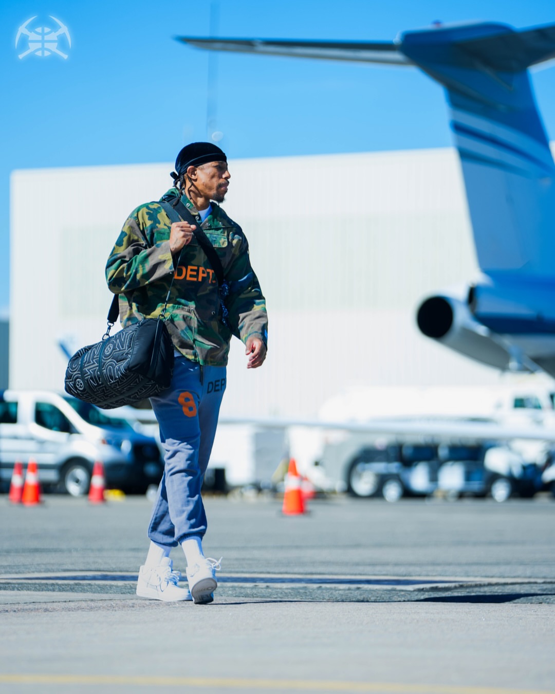 Russell Westbrook wearing Gallery Dept. Anorak camouflage print jacket green and orange, Gallery Dept. 8 Graphic print lounge bottoms grey and Nike Air jordan.