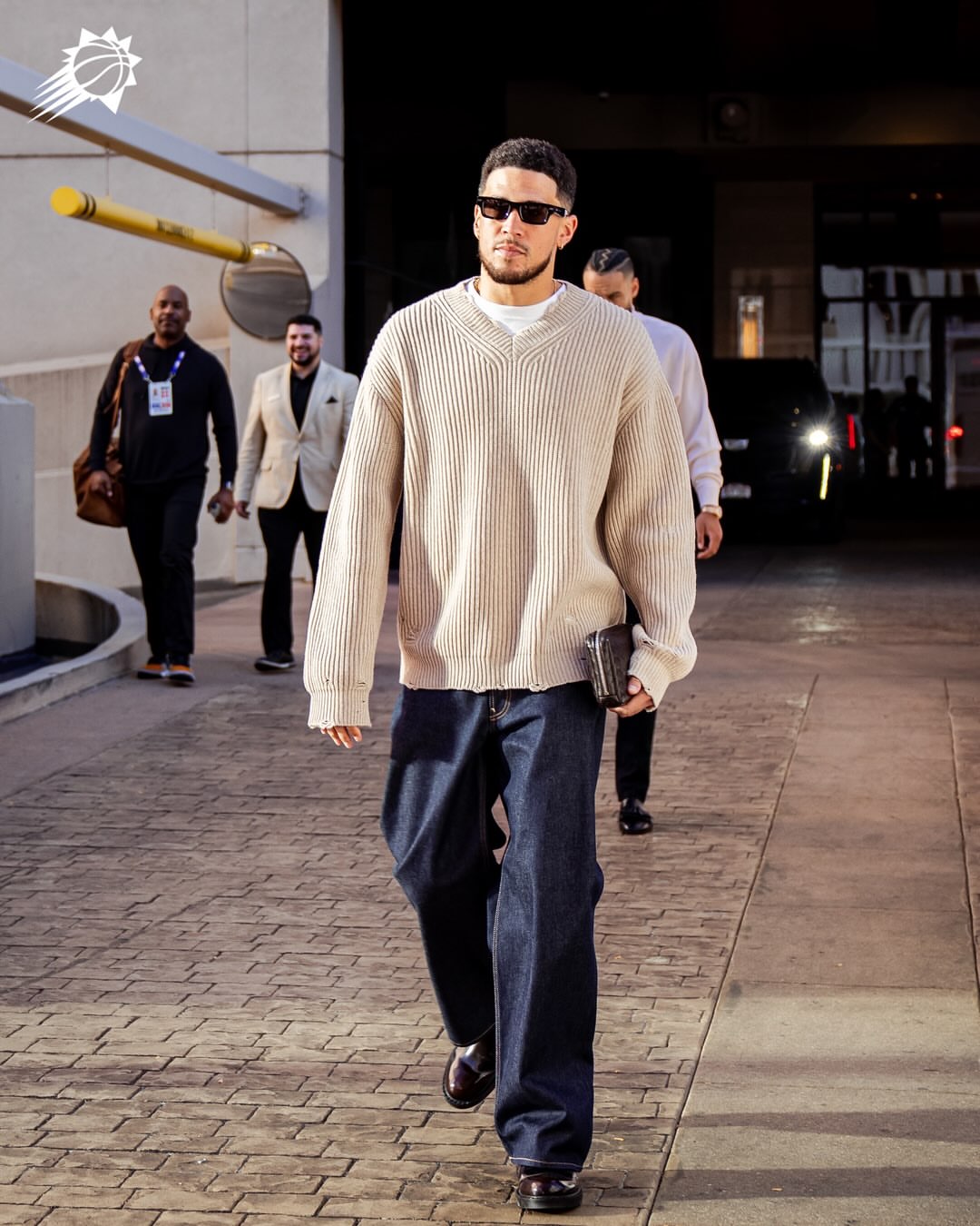 Devin Booker wearing Maison Margiela Distressed ribbed sweater Beige, Acne Studios 1981 Wide-leg jeans Deep blue and Dr. Martens 2976 Classic calf leather.